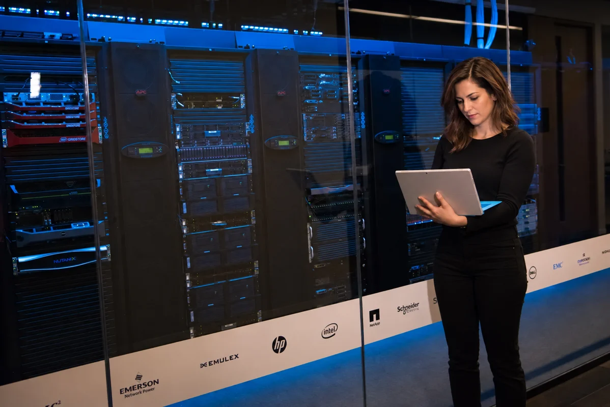 Engineer using a laptop beside server racks