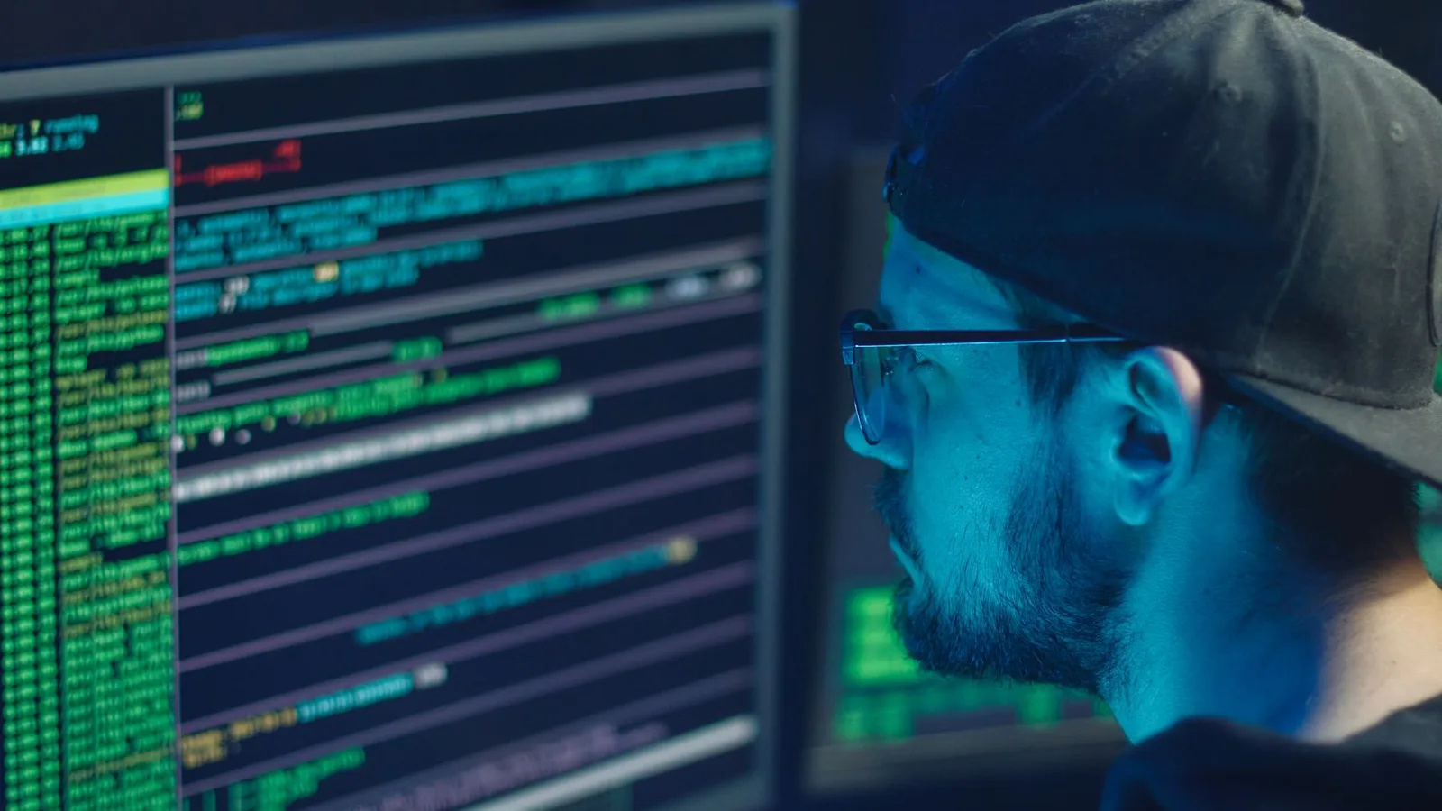 Cybersecurity professional reviewing terminal output on multiple monitors